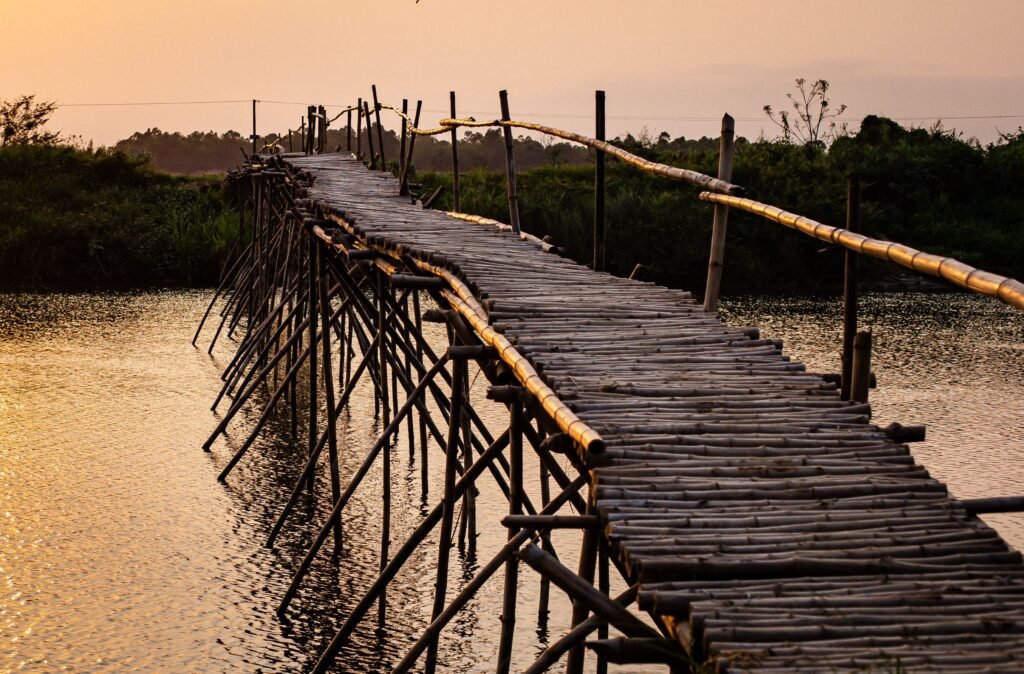 Captivating view of a bamboo bridge over a river at sunset in Hội An, Vietnam.