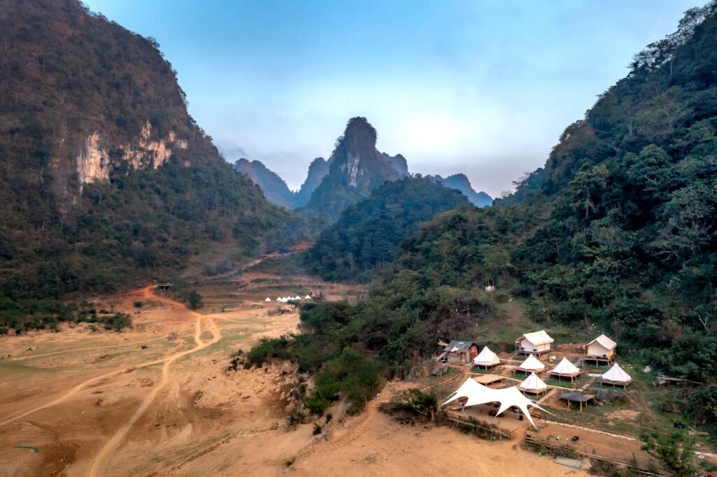 Aerial view of a campsite nestled in a picturesque mountain valley with surrounding lush greenery.