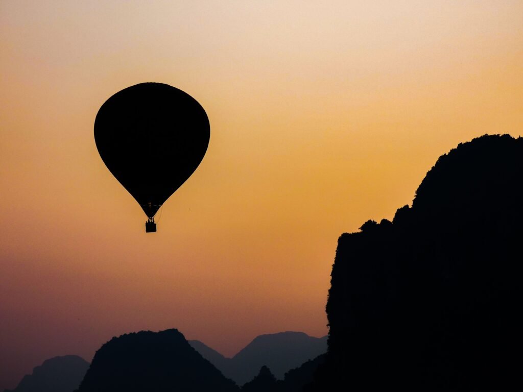 A hot air balloon floats in silhouette against a vibrant sunrise in Vang Vieng, Laos.