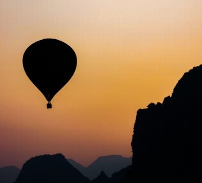 A hot air balloon floats in silhouette against a vibrant sunrise in Vang Vieng, Laos.