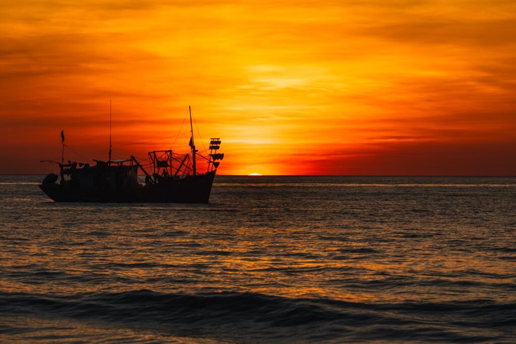 A fishing boat silhouette against a vibrant sunset over the sea in Quảng Trị, Vietnam.
