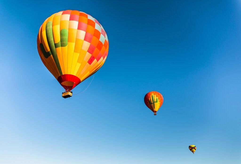 Vivid hot air balloons soar gracefully against a clear blue sky, offering a scenic view of air travel.