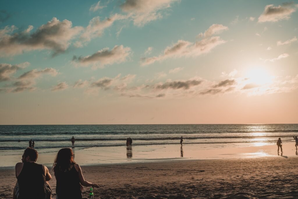 Beautiful sunset view on a Bali beach with people relaxing and enjoying the serene landscape.