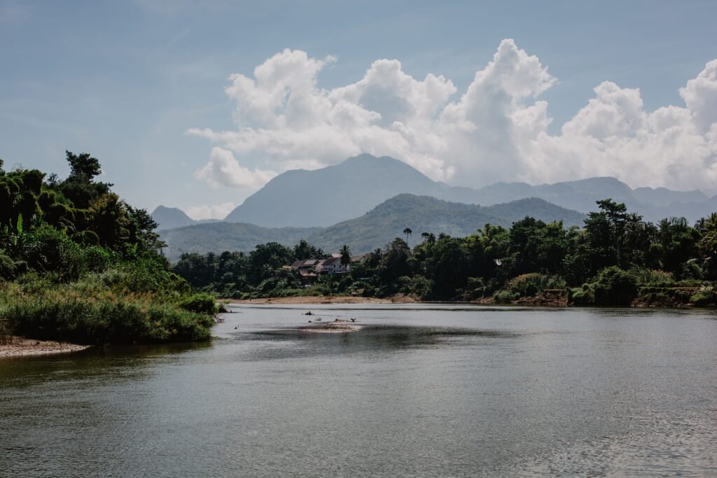 Amazing landscape of calm lake surrounded by tropical forest and high mountain ranges under beautiful cloudy sky