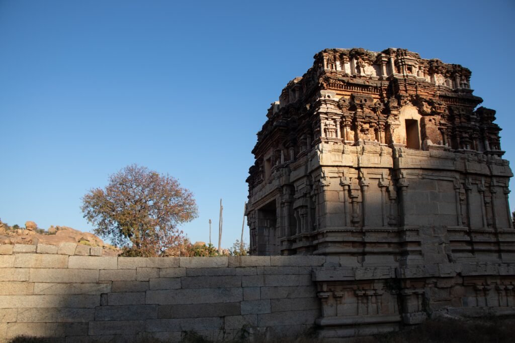Explore the ancient architectural beauty of a temple ruin in Hampi, India, under a clear blue sky.