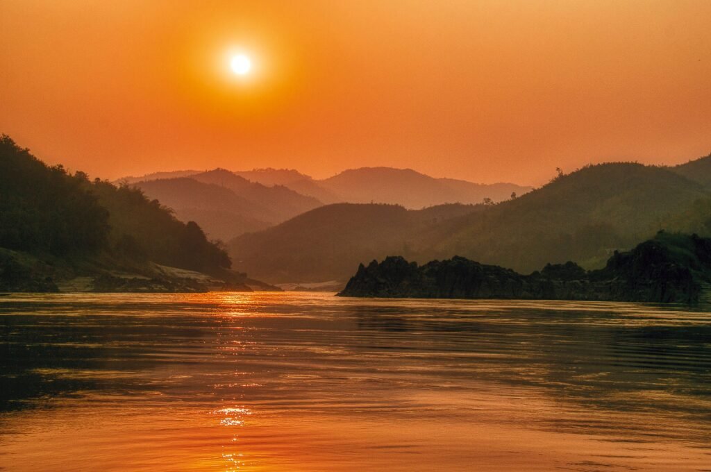 Serene sunset landscape over the Mekong River with scenic mountains in Bokeo Province, Laos.