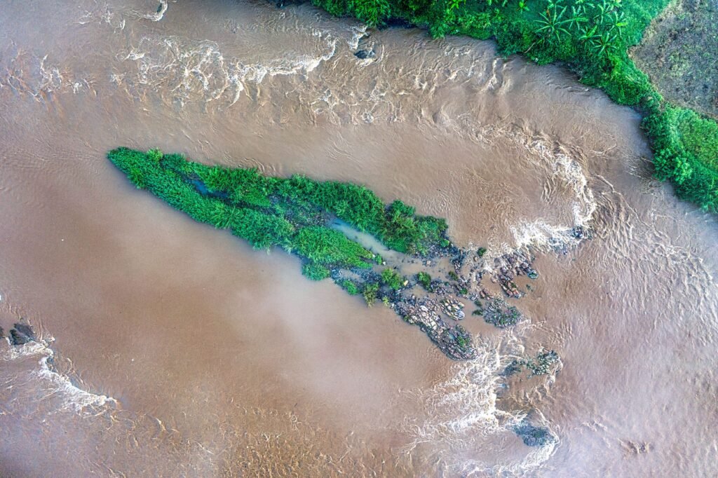 Aerial view of a lush green island surrounded by a flowing river in Banten, Indonesia.