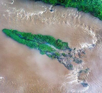 Aerial view of a lush green island surrounded by a flowing river in Banten, Indonesia.