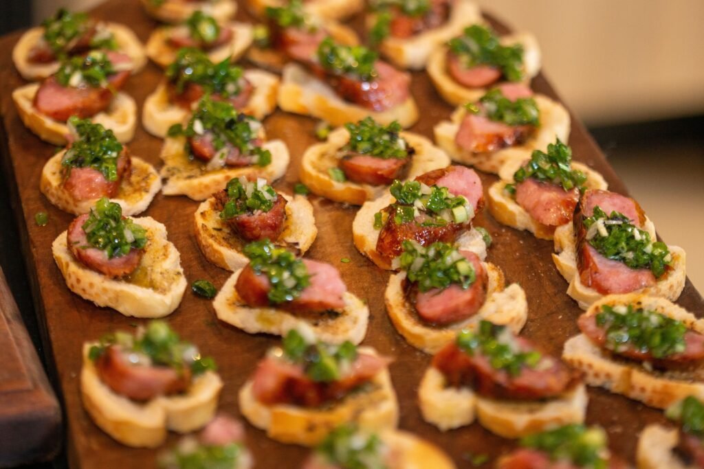 Delicious gourmet sausage canapés topped with fresh green herbs on bread slices.