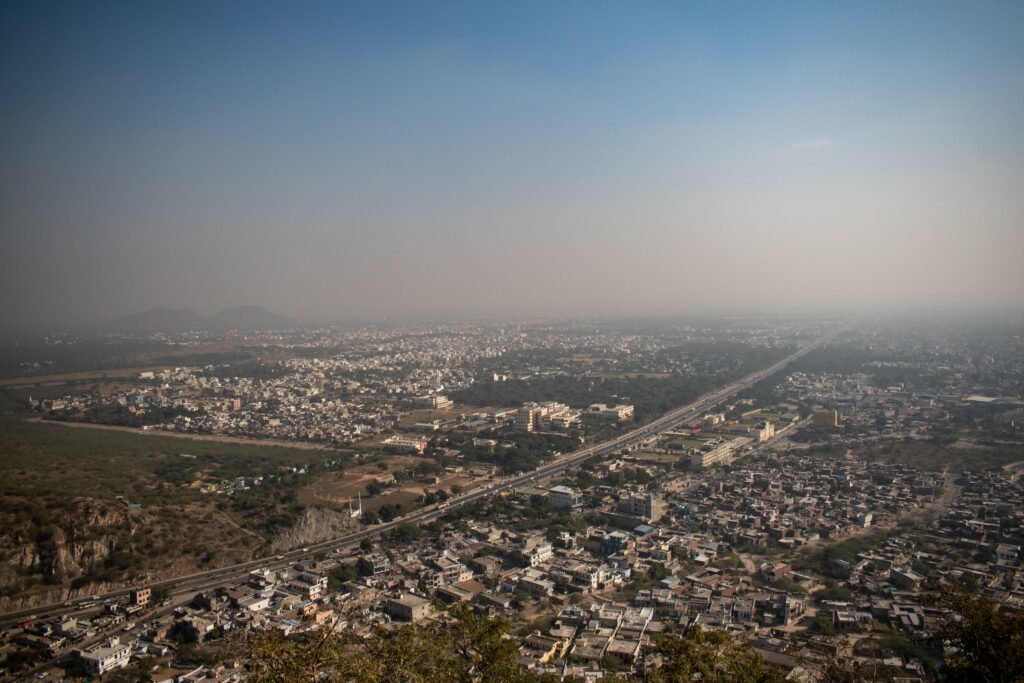 Aerial view of Jaipur city, showcasing the expansive urban landscape under a clear blue sky.