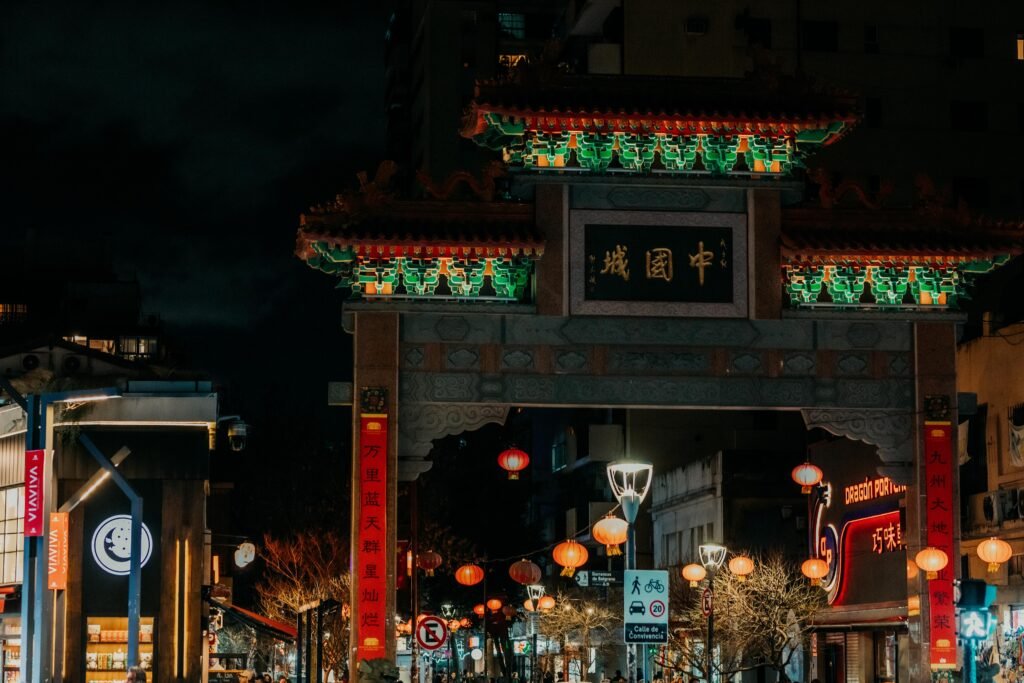 Vibrant night scene of a beautifully lit traditional Chinese archway in a bustling city Chinatown.