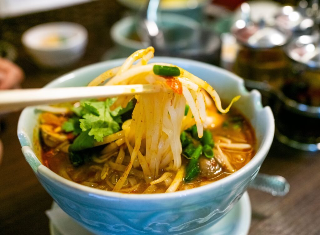 Savor a bowl of Thai noodle soup garnished with fresh herbs and chili, capturing the essence of Asian cuisine.