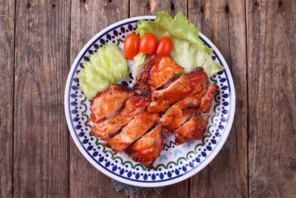 Tasty grilled chicken served with lettuce, tomato, and cucumber on a plate.