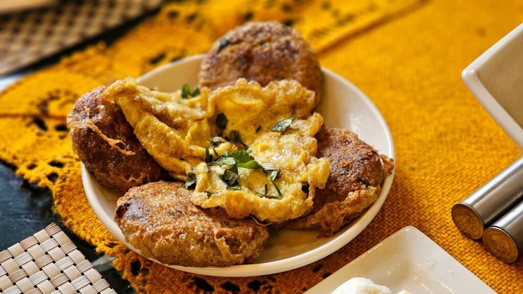 Appetizing homemade fritters topped with a golden omelette on a textured yellow tablecloth.