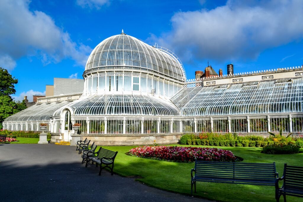 Exterior view of the historic Palm House at Belfast Botanic Gardens, showcasing Victorian architecture.