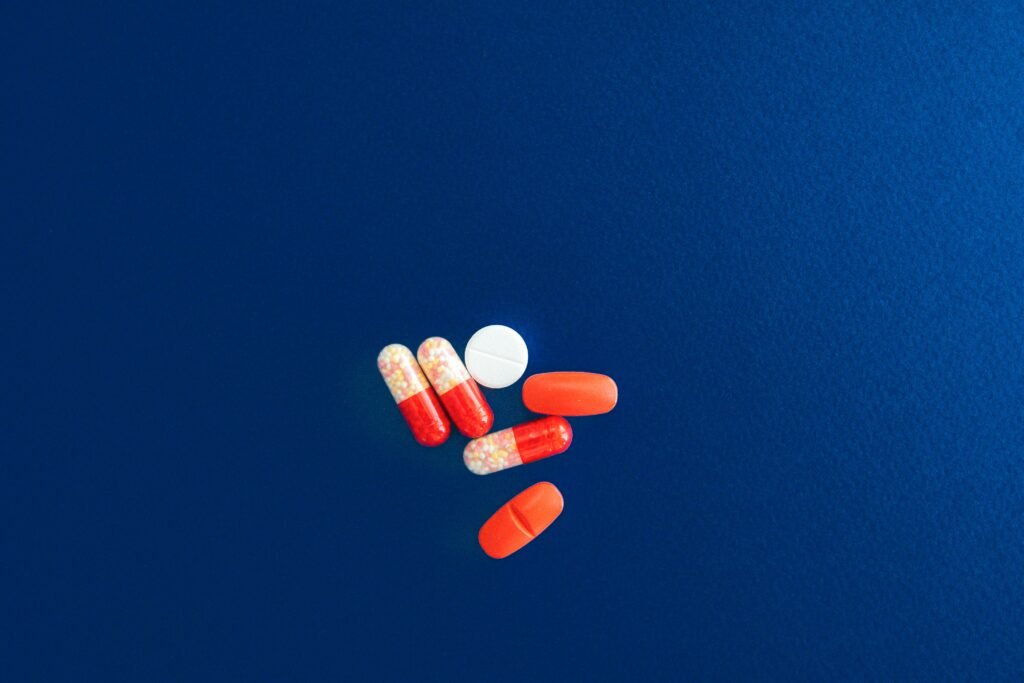 Assorted red and white capsules and tablets on a vivid blue surface.